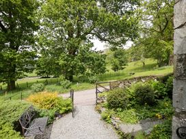 A garden view with trees and path at Hollens Cottage in Grasmere