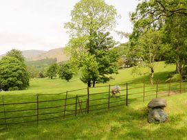 An outdoor scene with trees and a sheep near a fence at Hollens Cottage in Grasmere