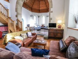 A living room with a sofa and staircase at Church Llygad Y Dyffryn Sarnau near Brynhoffnant