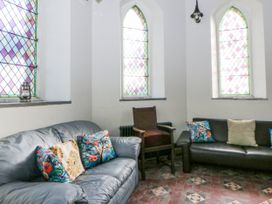 A snug area with a sofa and stained glass windows at Church Llygad Y Dyffryn Sarnau near Brynhoffnant