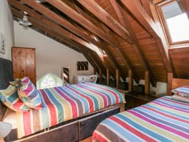 A bedroom with two beds, a nightstand, and a window at Church Llygad Y Dyffryn in Sarnau near Brynhoffnant