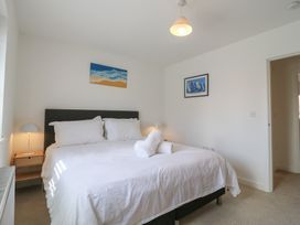 A bedroom with a bed, bedside table, and wall art at Inishnee House in Shotley Gate