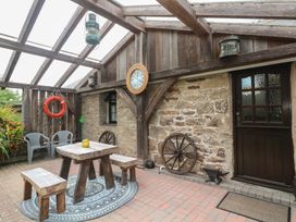 An outdoor seating area with a table and chairs at Horseshoe Cottage near Holywell Bay