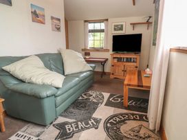 A living room with a sofa and television at Horseshoe Cottage near Holywell Bay