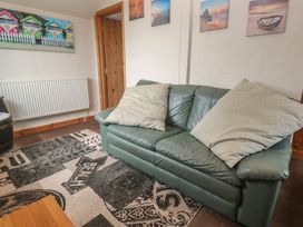 A living room with a sofa and wall art at Horseshoe Cottage Near Holywell Bay
