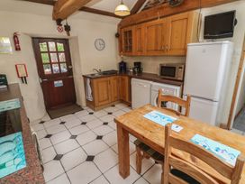A kitchen with wooden cabinets and appliances at Horseshoe Cottage Near Holywell Bay