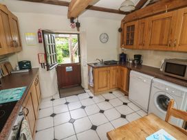 A kitchen with wooden cabinets and appliances at Horseshoe Cottage Near Holywell Bay