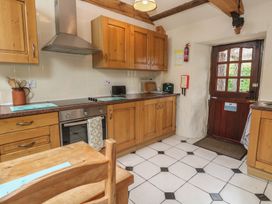 A kitchen with wooden cabinets and a door at Horseshoe Cottage near Holywell Bay