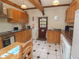 A kitchen with wooden cabinets and appliances at Horseshoe Cottage near Holywell Bay