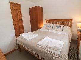 A bedroom with a bed and bedside table at Horseshoe Cottage Near Holywell Bay