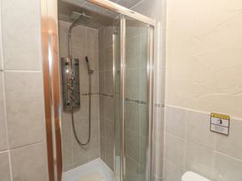 A shower with glass sliding door and controls at Horseshoe Cottage Near Holywell Bay