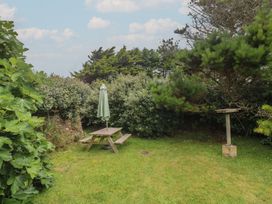 A garden with a picnic table and an umbrella at Horseshoe Cottage near Holywell Bay