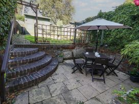 A garden with a patio, table, chairs, and steps at Miller's Cottage in Puddletown