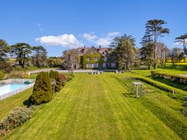 An outdoor area with a house, swimming pool, and trees at Alston Hall Battisborough Cross