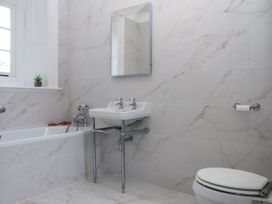 A bathroom with a bathtub, sink, toilet, and mirror at Alston Hall Battisborough Cross