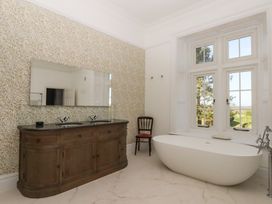 A bathroom with a bathtub, sink, and mirror at Alston Hall near Mothecombe Beach