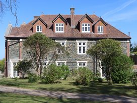 A stone building with multiple windows and trees at Alston Hall near Mothecombe Beach