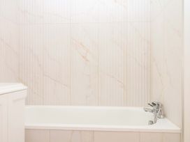 A bathroom featuring a bathtub and wall tiles at Alston Hall near Mothecombe Beach