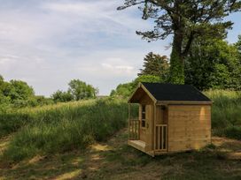 A wooden cabin in a grassy area with trees at Alston Hall near Mothecombe Beach
