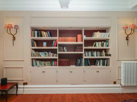 A bookshelf with books and a radiator at Alston Hall near Mothecombe Beach