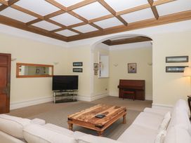 A living room with a sofa, coffee table, television, and piano at Alston Hall near Mothecombe Beach