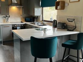 A kitchen with a sink, microwave, kettle, and two stools at Cowslip in Saltburn-By-The-Sea