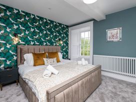 A bedroom with a bed and decorative wallpaper at Snowdonia Manor in Dolgellau