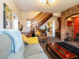 A living room with a sofa chair staircase and brick fireplace at Cobble Cottage in Great Ryburgh