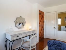 A bedroom corner with a white desk and chair mirror on the wall two doors and part of a bed at Cobble Cottage in Great Ryburgh
