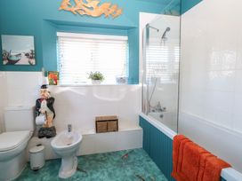 A bathroom with a toilet bidet bathtub and decorative figurine at Cobble Cottage in Great Ryburgh