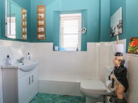 A bathroom with a white sink and cabinet a toilet a window with blinds and blue walls at Cobble Cottage in Great Ryburgh