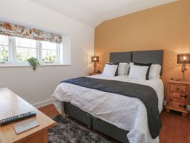 A bedroom with a bed lamps on wooden side tables a window with floral blind and a wooden table with a remote control at Cobble Cottage Great Ryburgh