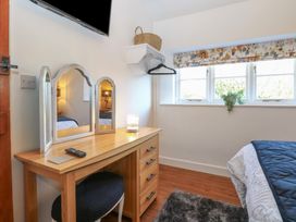 A bedroom with a wooden dressing table mirror and stool beside a bed and window at Cobble Cottage in Great Ryburgh
