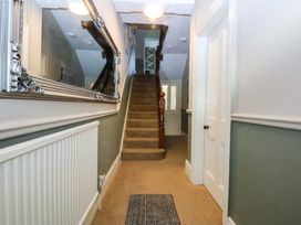 A hallway with a staircase and a mirror at Curzon Heights in Llandudno