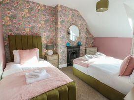 A bedroom with two beds and a mirror at Curzon Heights in Llandudno