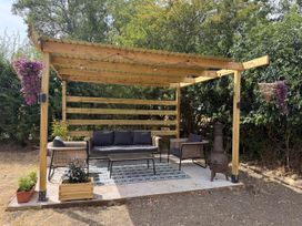 An outdoor seating area with a sofa and chairs under a pergola at Little Acre Church Lench near Harvington