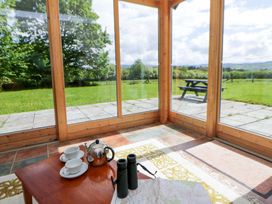A conservatory with a table set for tea and a view of the garden at Bryn Isaf in Swyddffynnon near Pontrhydfendigaid