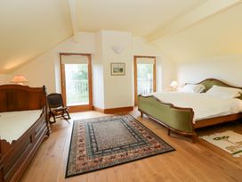 A bedroom with a bed, lamp, chair, and rug at Bryn Isaf in Swyddffynnon near Pontrhydfendigaid