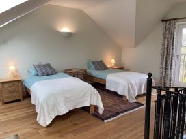 A bedroom with two beds and a balcony door at Ty Cellin in Ystrad Meurig