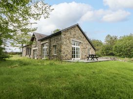 A stone house with a picnic table and grass lawn at Ty Cellin in Swyddffynnon near Pontrhydfendigaid