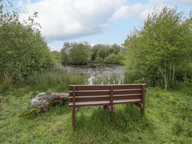 A scenic view with a bench overlooking a pond surrounded by trees and grass at Ty Cellin in Swyddffynnon near Pontrhydfendigaid