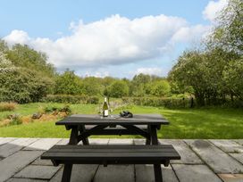 A table with a bottle and glasses in a garden at Ty Cellin in Swyddffynnon near Pontrhydfendigaid
