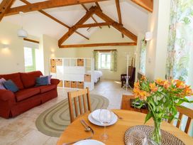 An open plan room with a red sofa a wooden dining table with plates and glasses flowers on the table a bed in the background and exposed wooden beams at Cwtch in Swyddffynnon near Pontrhydfendigaid