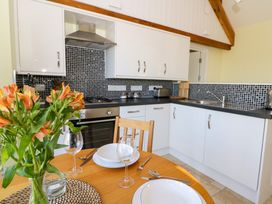 A kitchen with white cabinets black countertop and tiled backsplash with a dining table with plates glasses and flowers at Cwtch in Swyddffynnon near Pontrhydfendigaid
