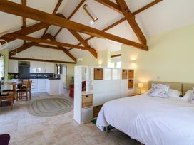 An open-plan room with a bed, white storage unit, dining table, kitchen area, and visible wooden ceiling beams at Cwtch in Swyddffynnon near Pontrhydfendigaid