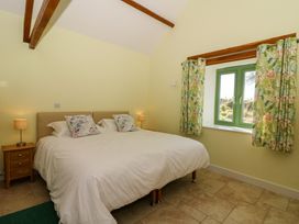A bedroom with a double bed two bedside tables with lamps and a window with floral curtains at Cwtch in Swyddffynnon near Pontrhydfendigaid