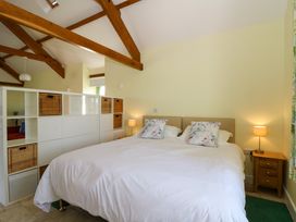 A bedroom with a double bed white bedding floral pillows bedside tables and white storage unit with wicker baskets at Cwtch in Swyddffynnon near Pontrhydfendigaid