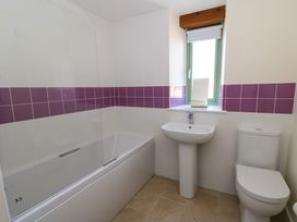 A bathroom with a bathtub a sink a toilet and a window with purple tiled walls at Cwtch in Swyddffynnon near Pontrhydfendigaid