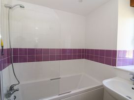 A bathroom with a bathtub shower combo with purple and white tiled walls at Cwtch in Swyddffynnon near Pontrhydfendigaid
