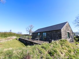 A stone building with a slate roof and green doors surrounded by grass and trees at Cwtch in Swyddffynnon near Pontrhydfendigaid